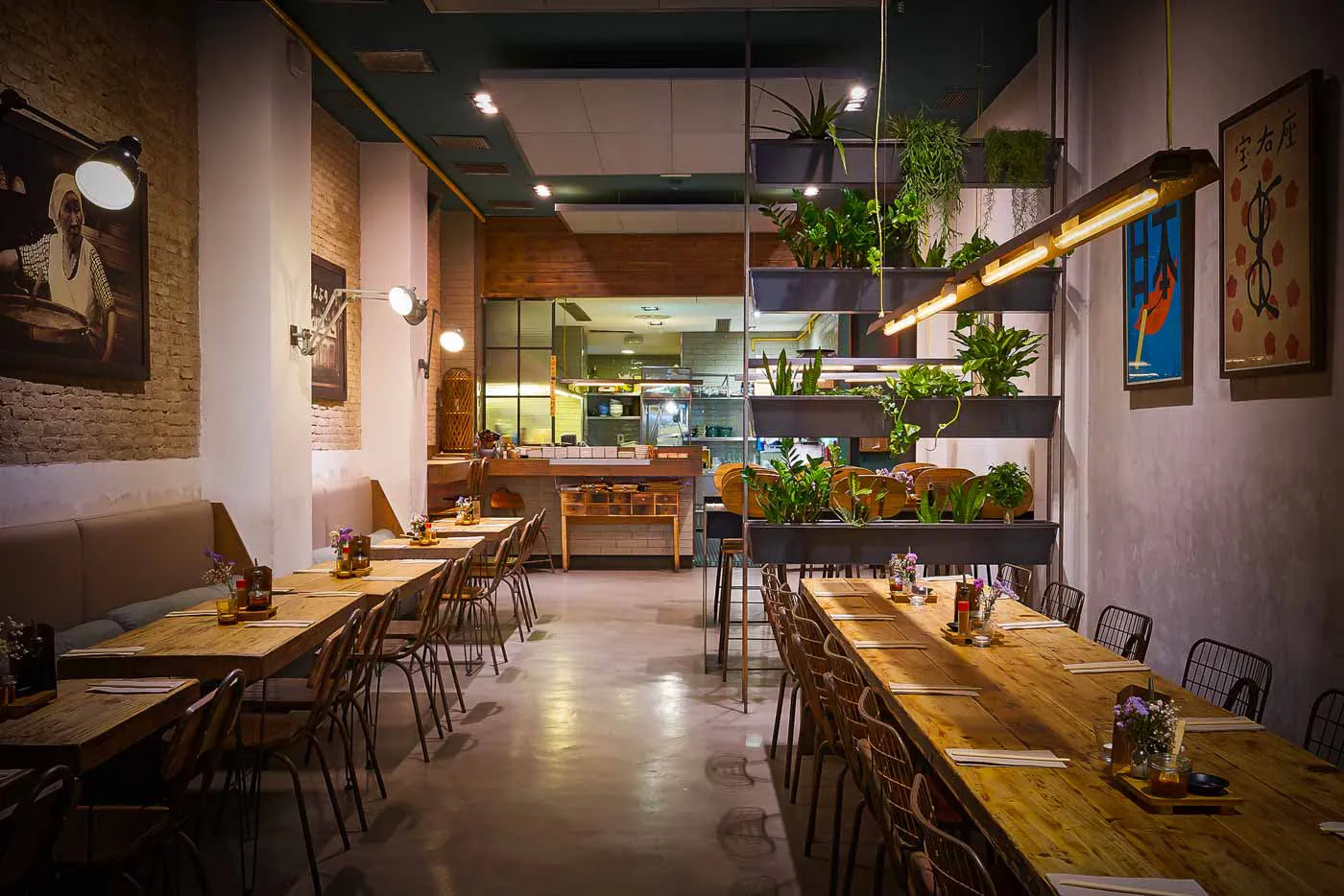 The long wooden tables and hanging plants of the dining room at Koku Kitchen El Born